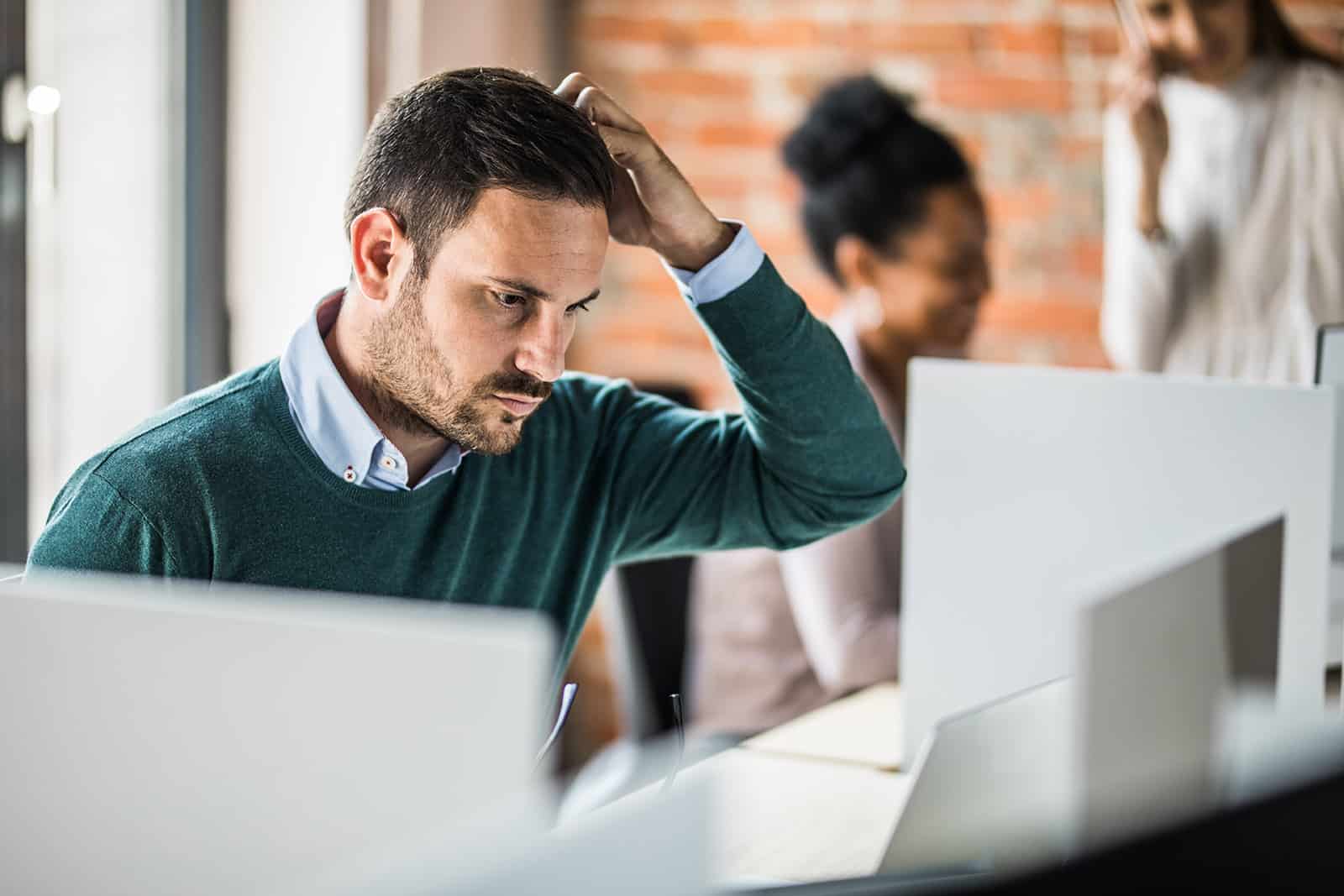 Man sitting in front of a computer looking concerned.